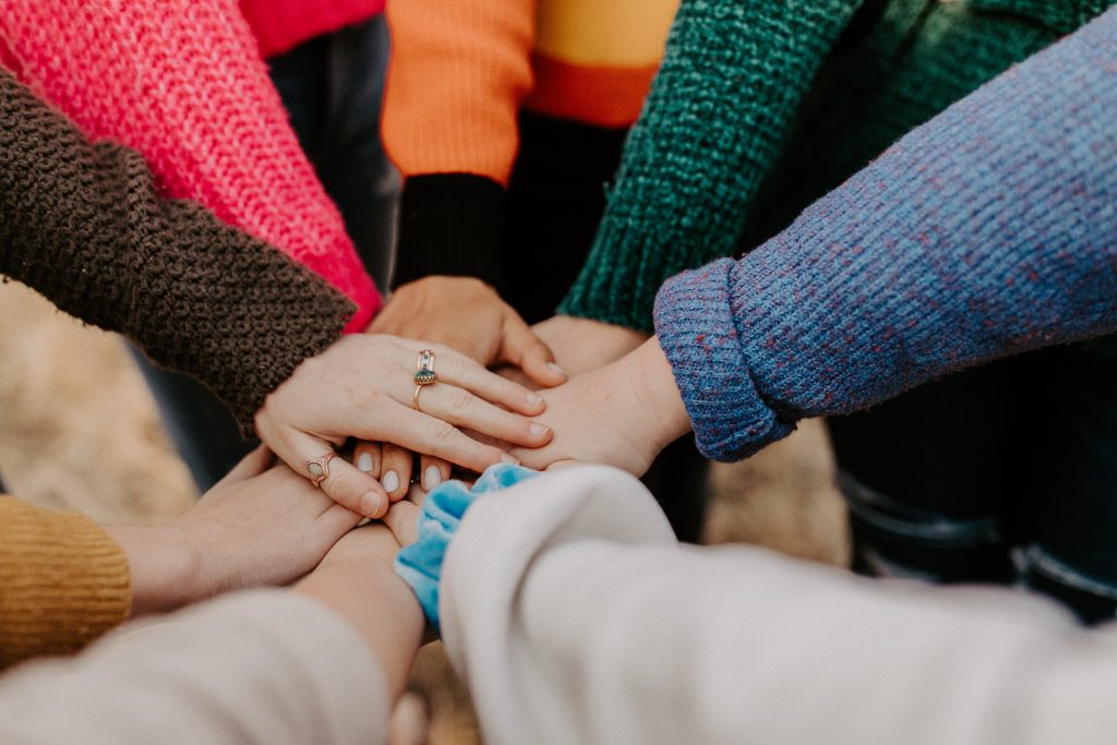 A group of people put their hands together in a pact like manner.